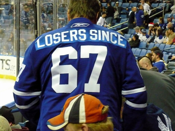 The broad back of a player wearing a royal blue jersey, number '67, has the words Losers Since 67 across his shoulders.