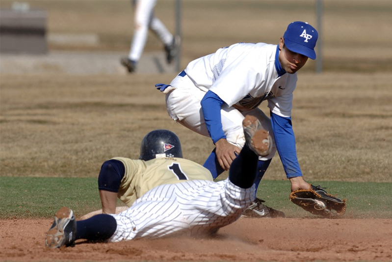 Baseball player slid onto a base with another player hovering over him
