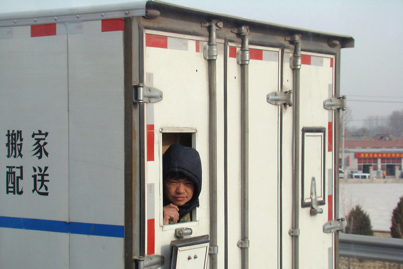 Young boy looking through a window in the back of a delivery truck