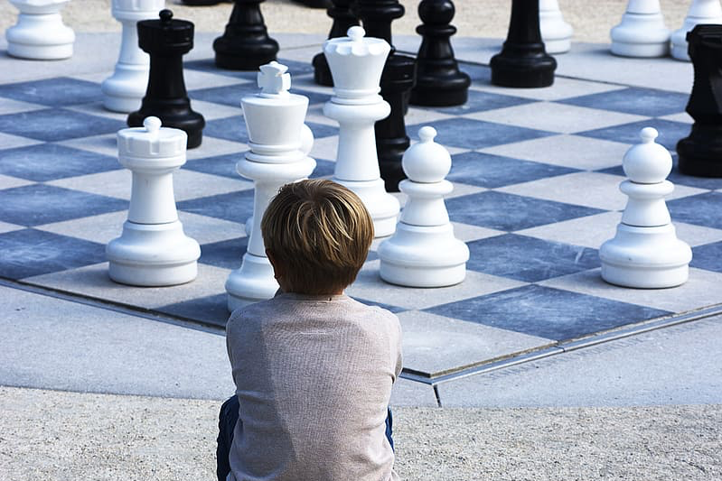 Young boy sitting before a giant-sized chessboard