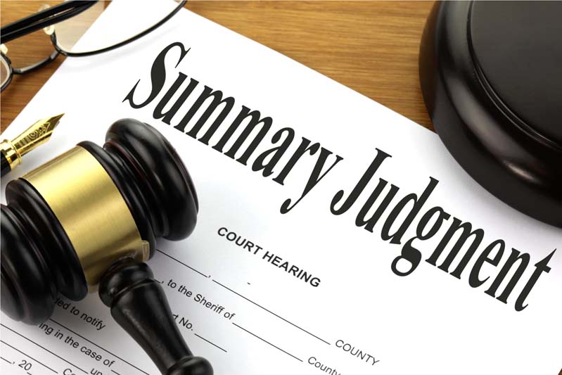 A picture of a court hearing form with summary judgment written at the top together with a gavel, block, pen and glasses.