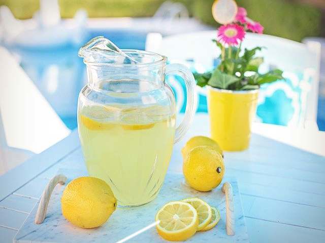 Lemonade in a pitcher on a white-clothed table next to a pool