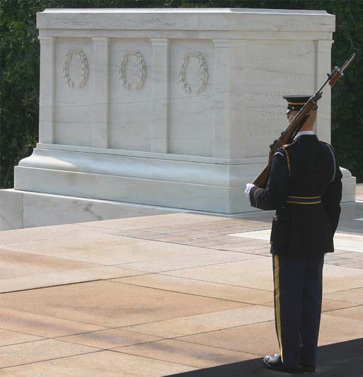 A sentry stands before the white rectangular tomb.