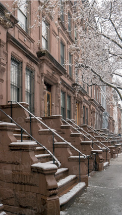 An early spring day looking down the sidewalk at a row of townhouses.