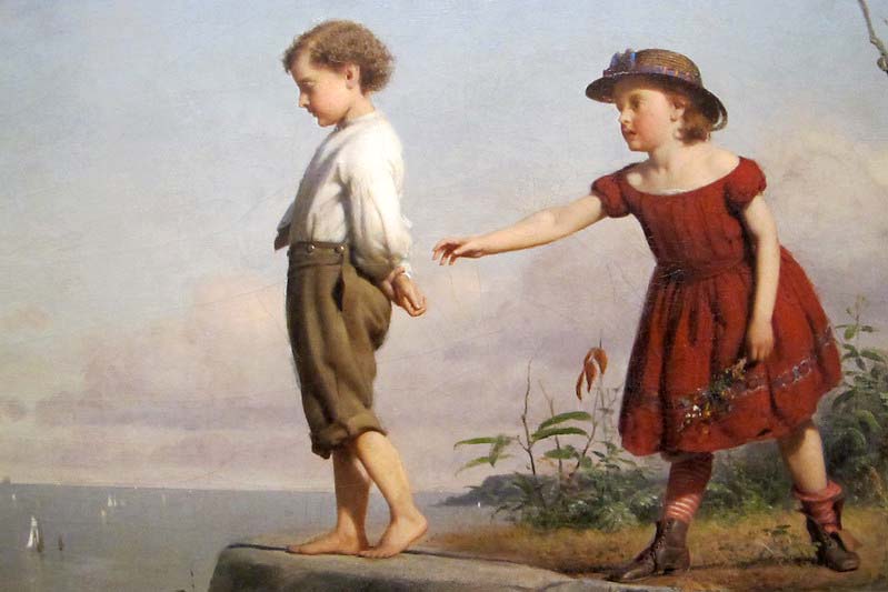 A boy stands lookint out at the edge of a cliff while a girl is behind him with an arm reaching for his back.