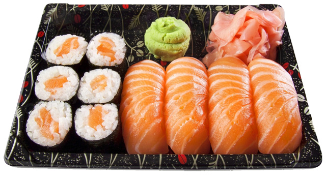 On a black leaf-printed tray are, from left, two rows of six seaweed-wrapped rice rolls with salmon in the center and then four salmon sashini at the front of the tray. A mound of green wasabi is behind the salmon on the left with a pile of pink shaved pickled ginger on the right.